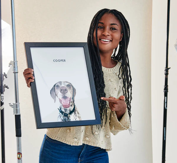 Smiling woman holding a custom pet portrait of her Dalmatian dog by Paw-Pixie, showcasing a personalized framed artwork.