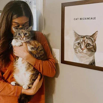 A woman holding her cat beside a custom pet portrait frame by Paw-Pixie, featuring the cat named Beckinsale.